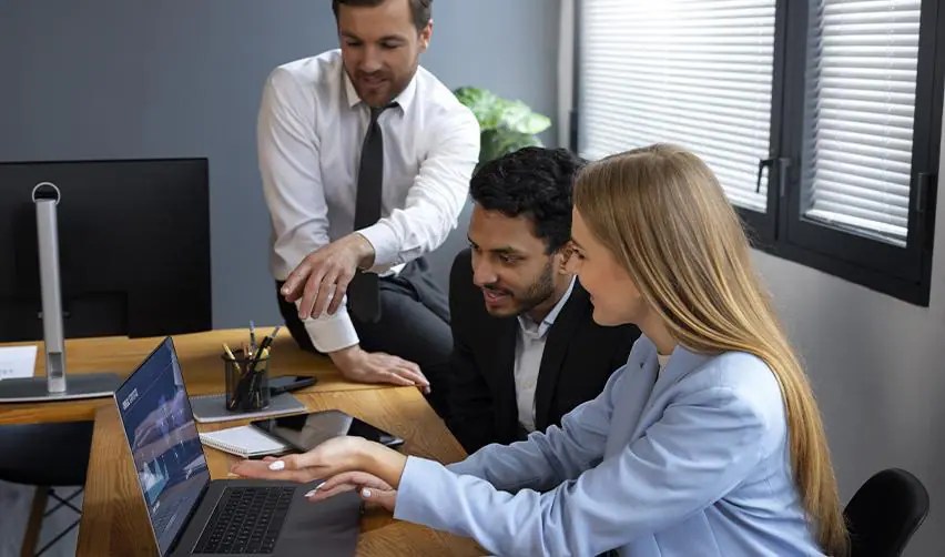 A team of professionals reviewing project details on a laptop, symbolizing collaboration between EB5 investors, regional centers, and advisors in structuring transactions.